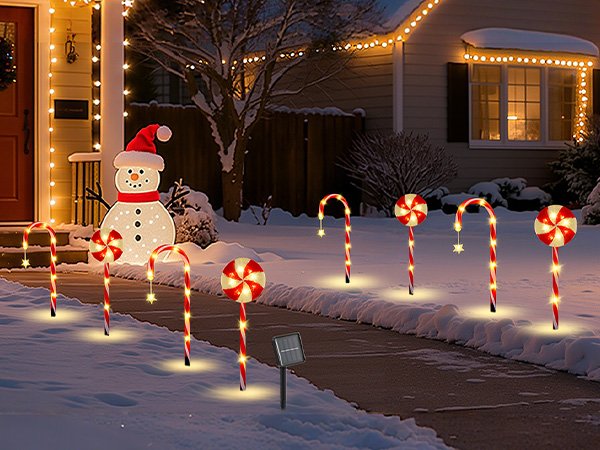 Christmas candy cane and lollipop pathway lights with a snowman decoration in front of a house at night.