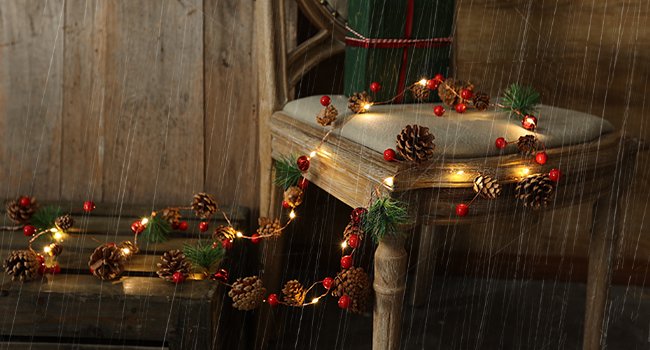 Christmas garland with pinecones, red berries, and LED lights draped over a chair and wooden surface, with a rain effect overlay.