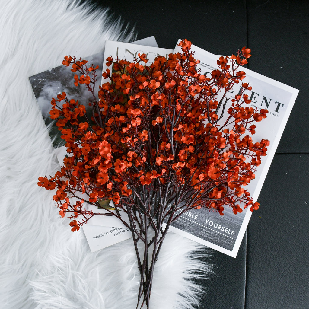 Burnt orange artificial baby's breath flowers arranged on magazines and white faux fur