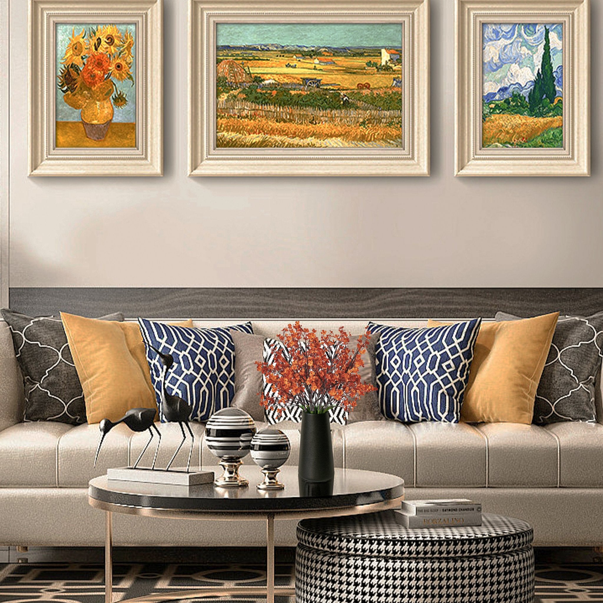 Three framed paintings of landscapes and sunflowers displayed above a sofa with decorative pillows and a coffee table.
