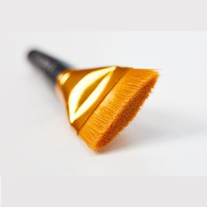 Flat paint brush with golden ferrule and black handle, angled view on white background
