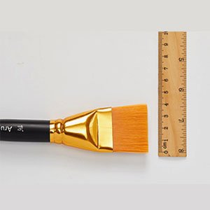 Flat paint brush with wooden handle and gold ferrule next to a wooden ruler for scale