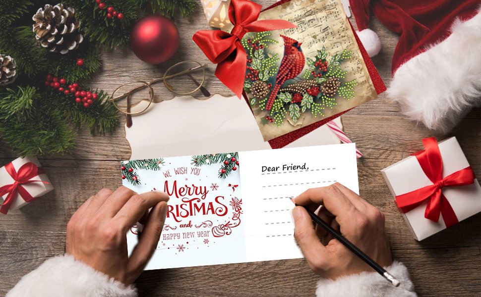 Hands writing a Christmas card with a cardinal design, surrounded by festive decorations and gifts.