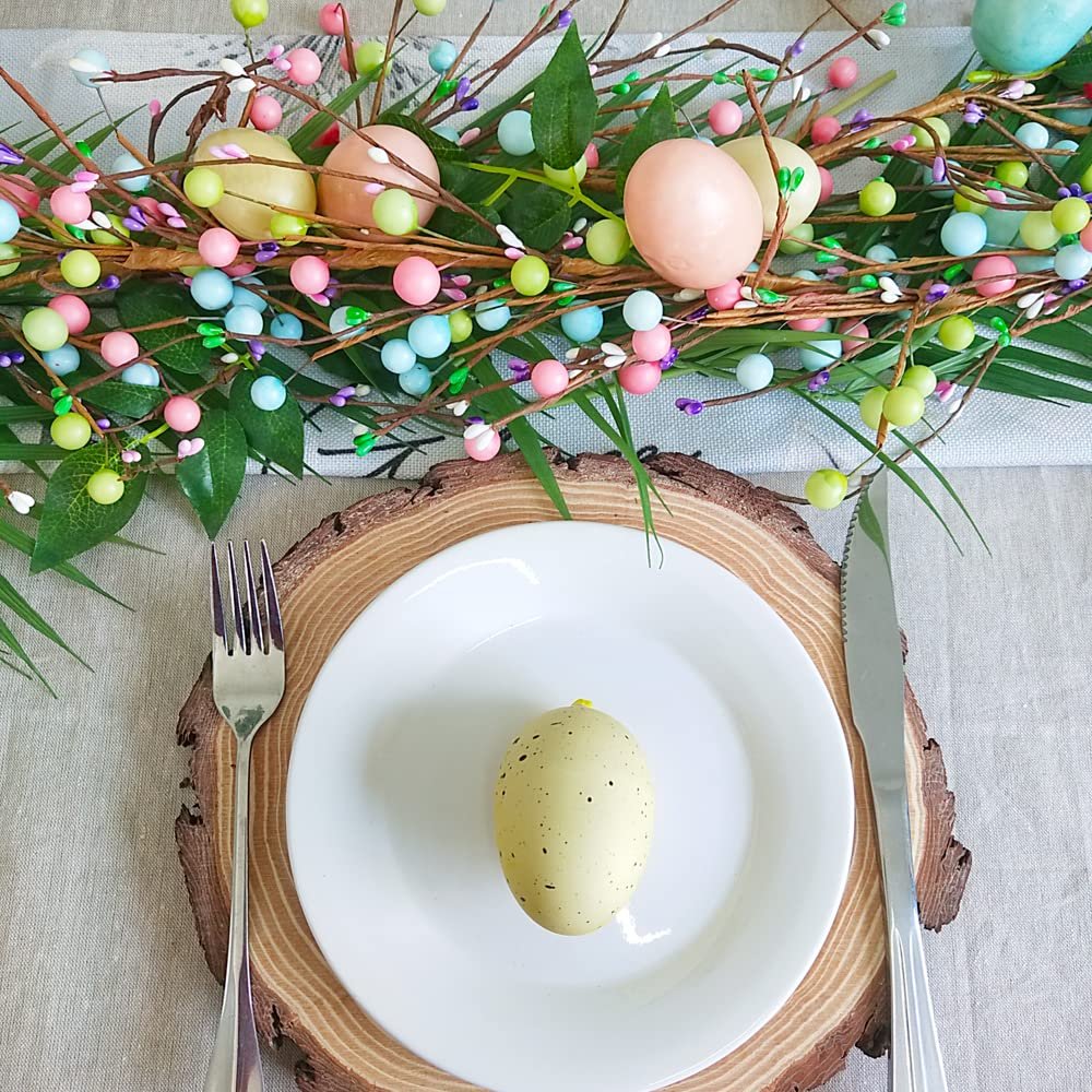 Easter table setting with a pastel egg and berry garland draped over a placemat and plate.