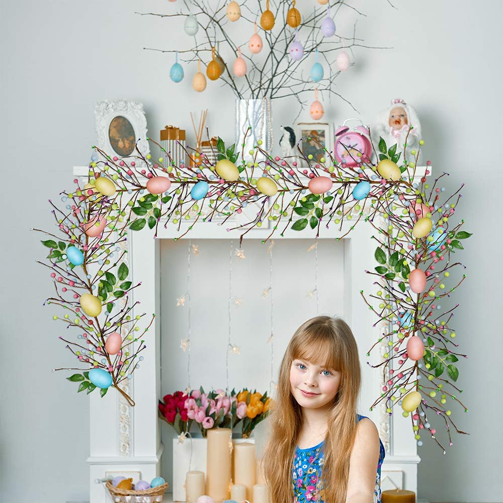 Young girl in blue dress in front of a decorated fireplace with Easter egg garland and branches with eggs