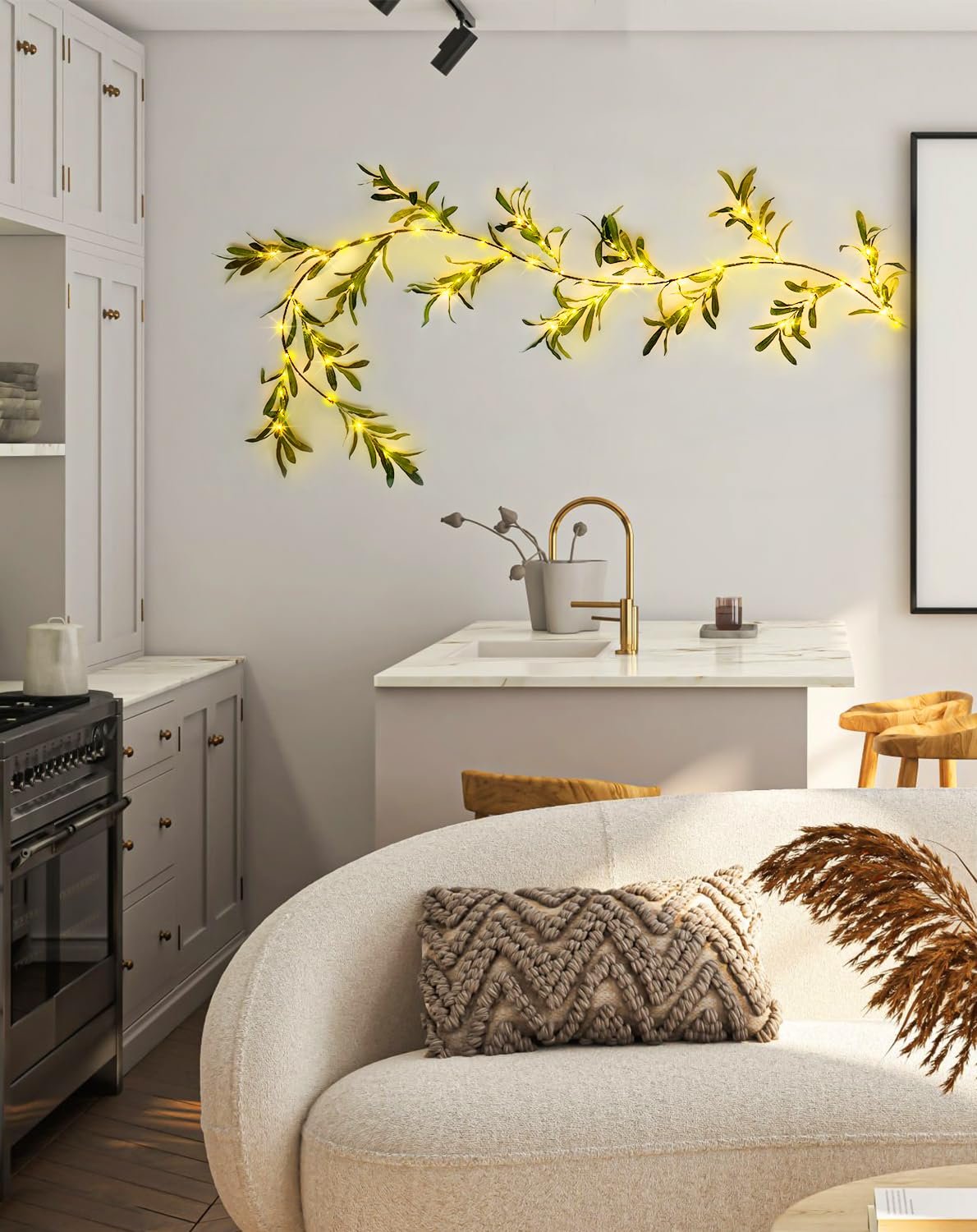 Artificial olive garland with warm white fairy lights draped on a kitchen wall above a counter and sofa.