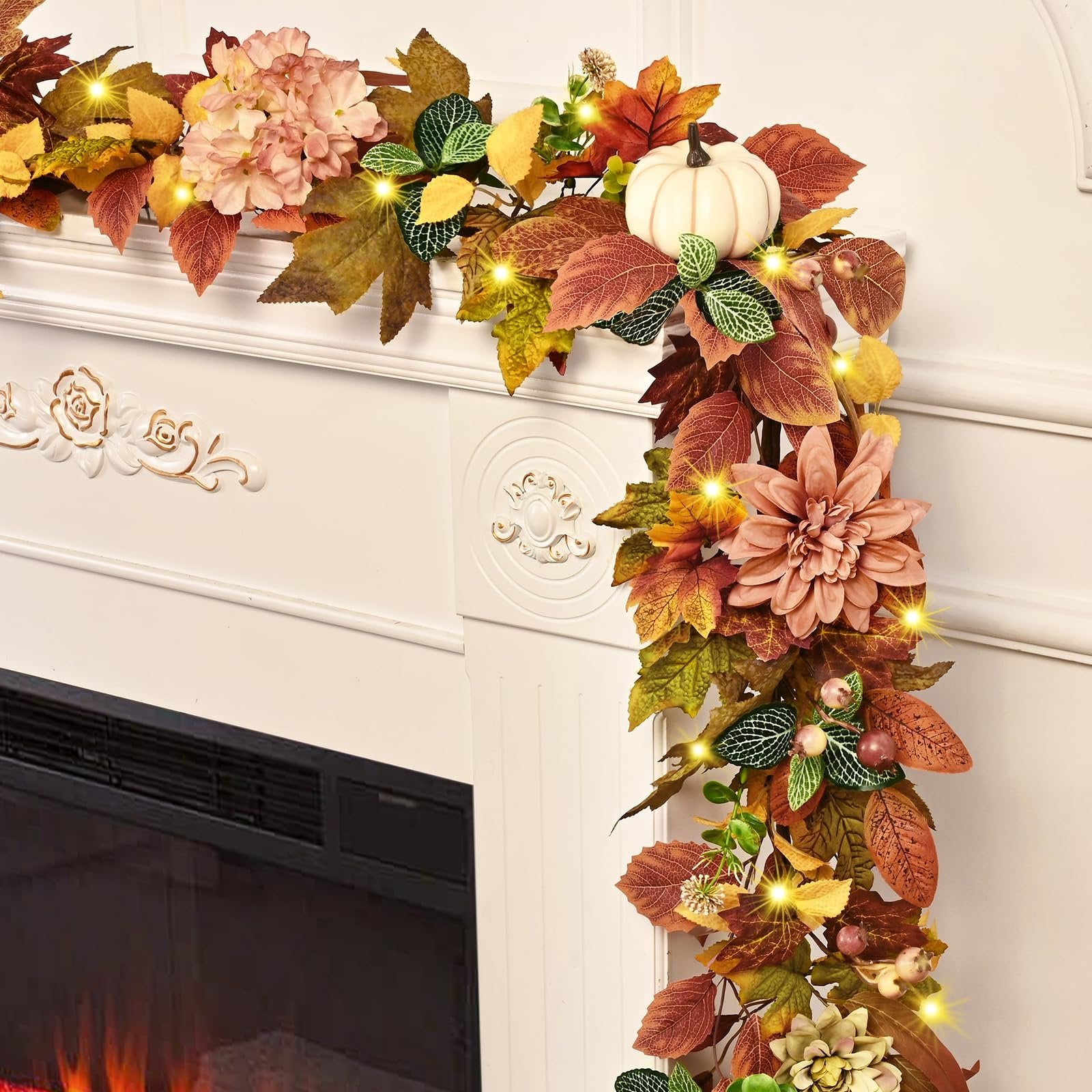 Autumn garland with lights, artificial leaves, flowers, and a white pumpkin draped over a fireplace mantle.