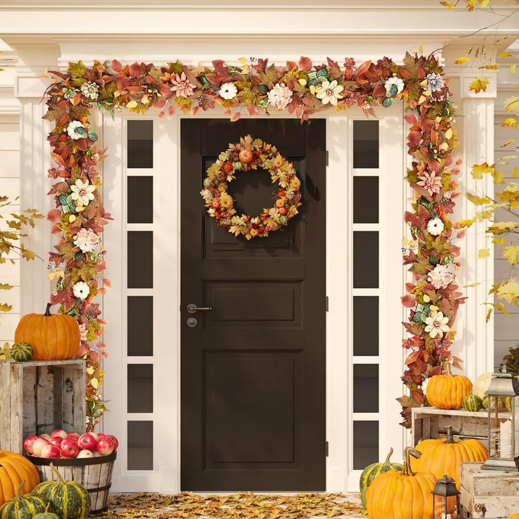 Front door decorated for fall with a garland of leaves and flowers, a wreath, pumpkins, and apples.