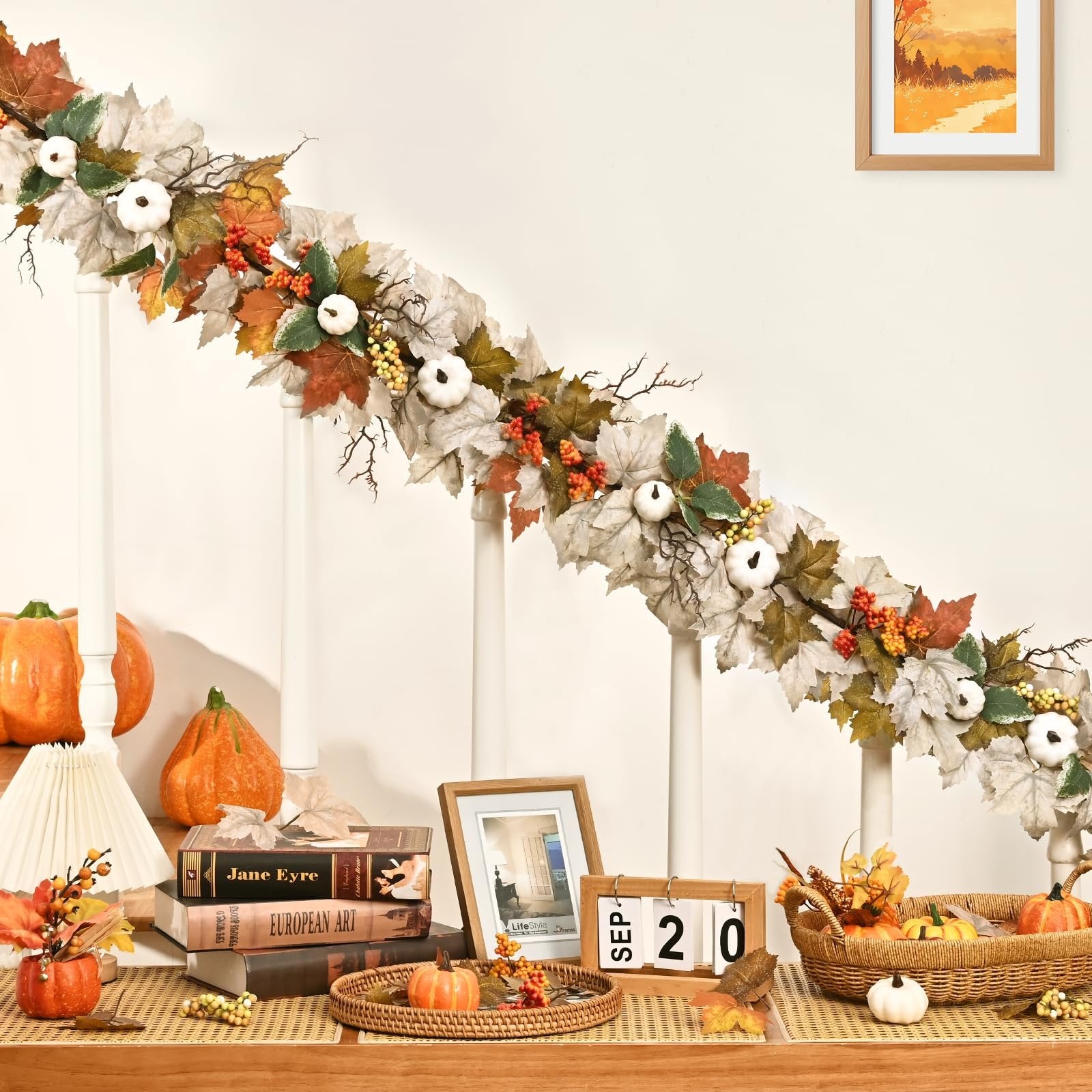 Autumn garland with maple leaves, white pumpkins, berries, and lights draped over a banister.