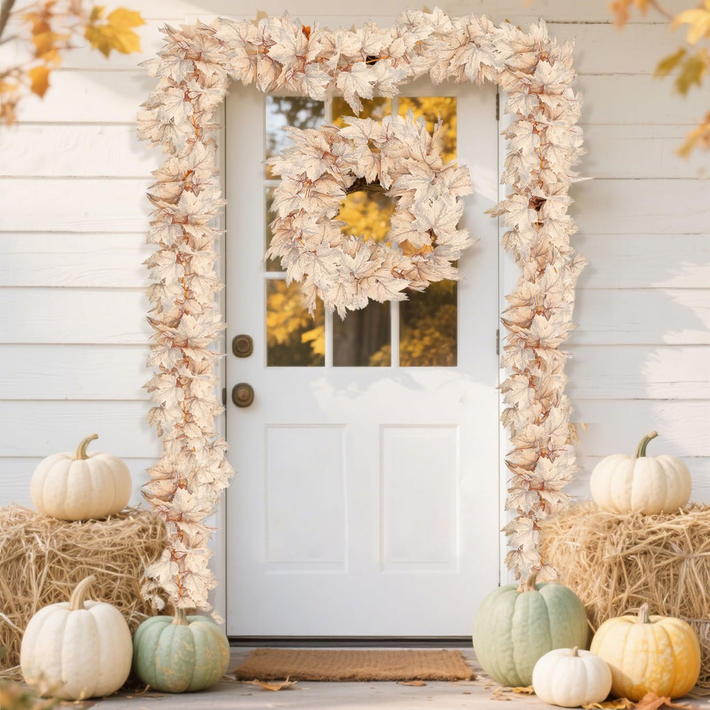 Autumn leaf garland and wreath decorating a white door with pumpkins and hay bales