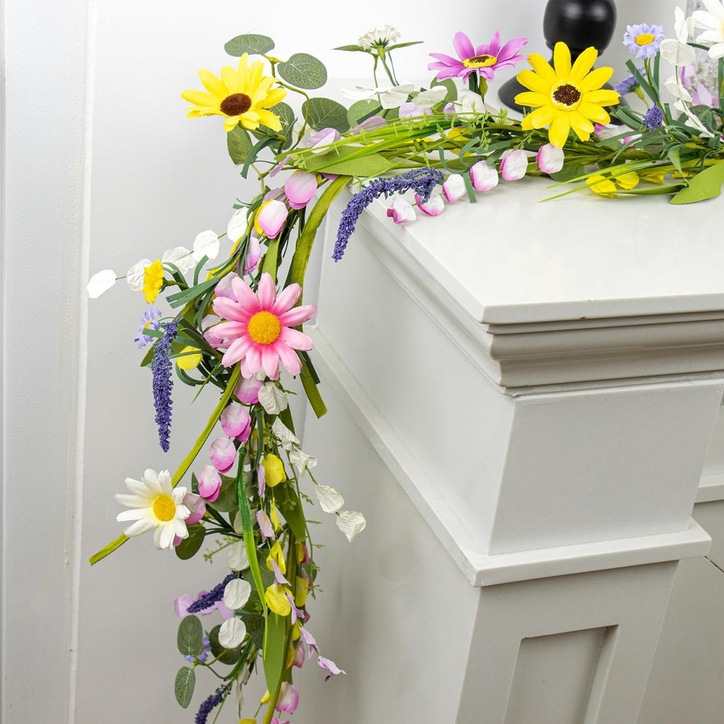 Farmhouse spring flower garland with pink, yellow, and white wildflowers draped over a white mantelpiece.
