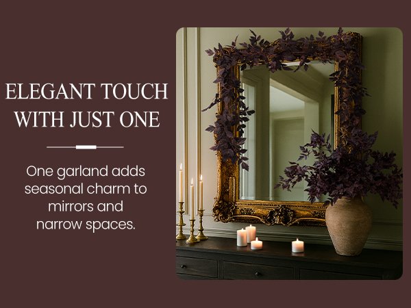 Dark purple artificial garland draped over an ornate gold mirror with candles and a vase below