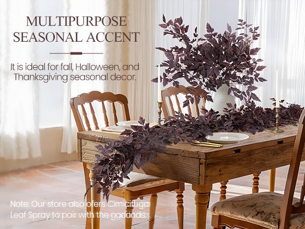 Fall garland with dark plum leaves draped across a rustic wooden dining table with place settings.