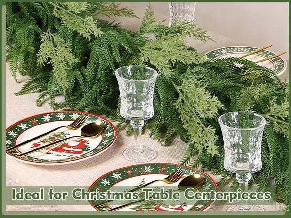 Christmas garland draped over a table setting with plates, cutlery, and glasses