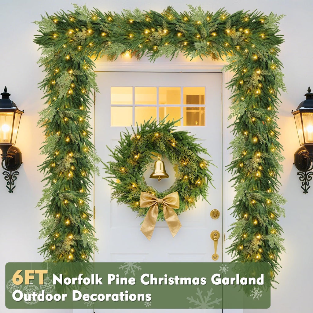 Prelit Christmas garland and wreath decorating a white door with lanterns on either side.