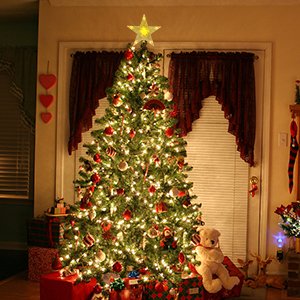 Lit Christmas tree with a warm white LED star tree topper, decorated with ornaments and presents below.