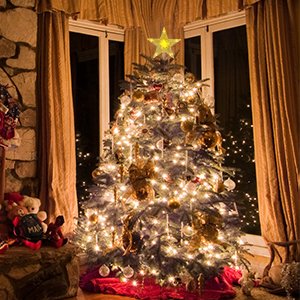 Illuminated Christmas tree topper star with warm white lights on a decorated Christmas tree.