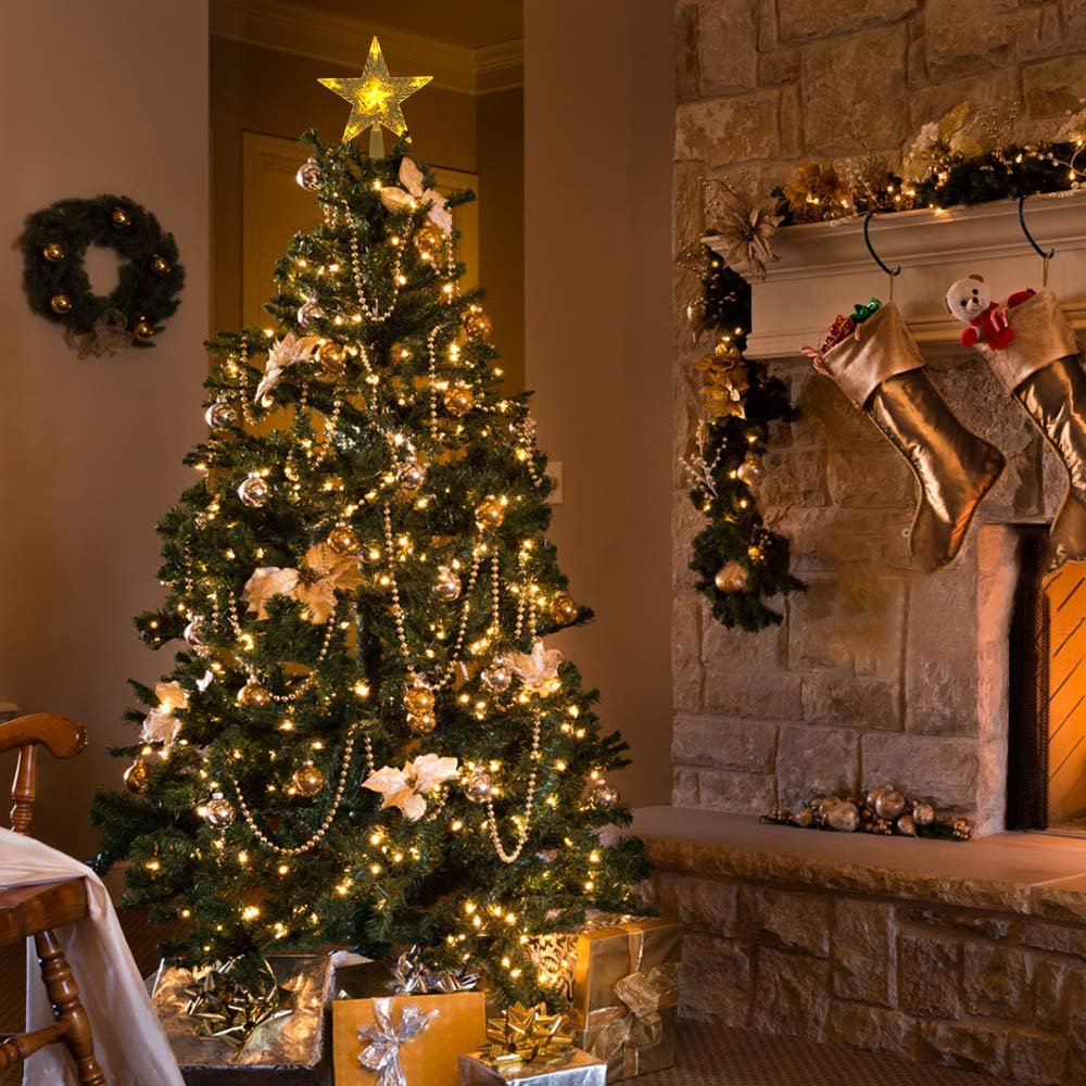 Decorated Christmas tree with a lighted star topper and presents underneath, next to a stone fireplace with stockings.