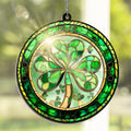 Round stained glass suncatcher with a shamrock design, hanging by a chain against a blurred green background.
