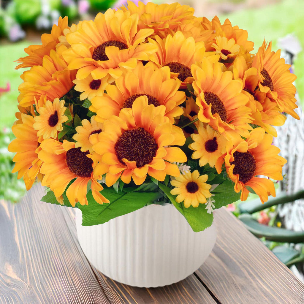 Artificial sunflowers in a white pot on a wooden table with a blurred garden background