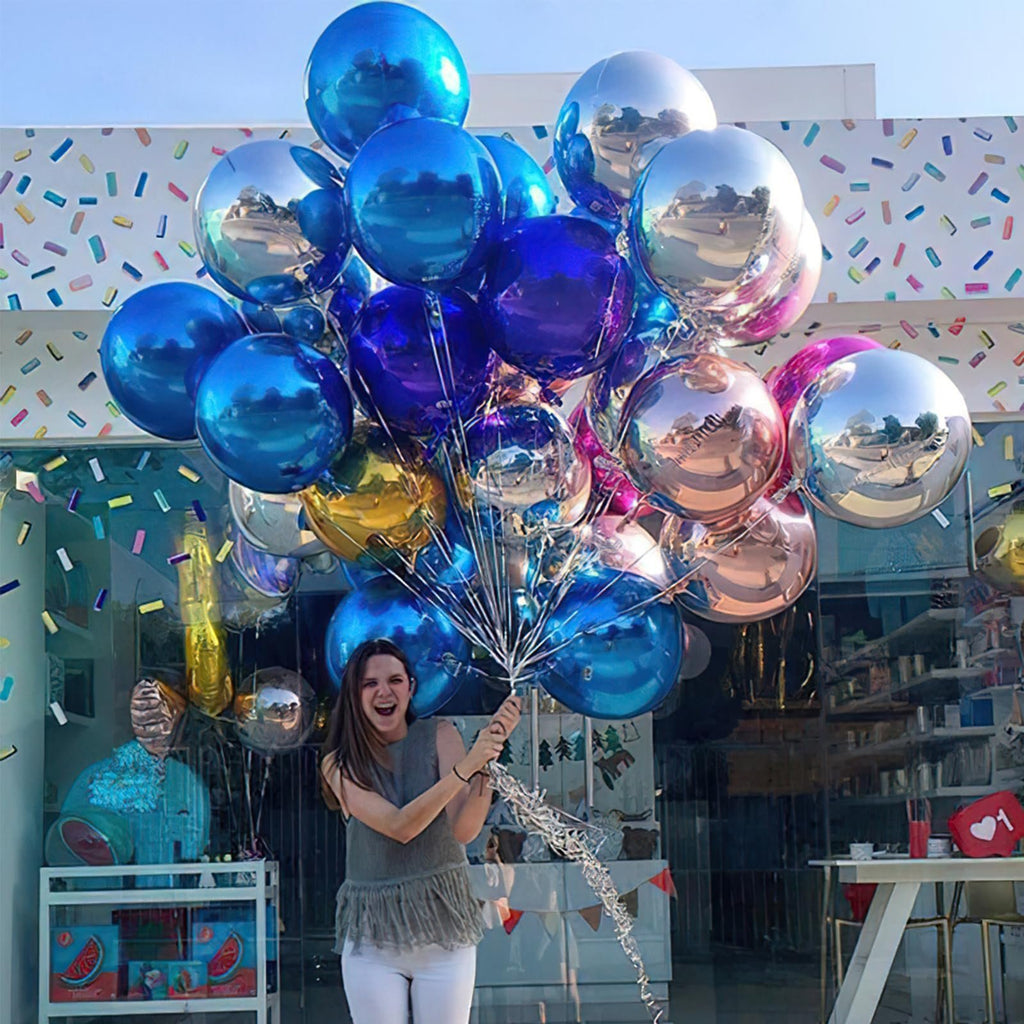 Woman holding a large bunch of round, reflective foil balloons in various shades of blue, silver, and rose gold.