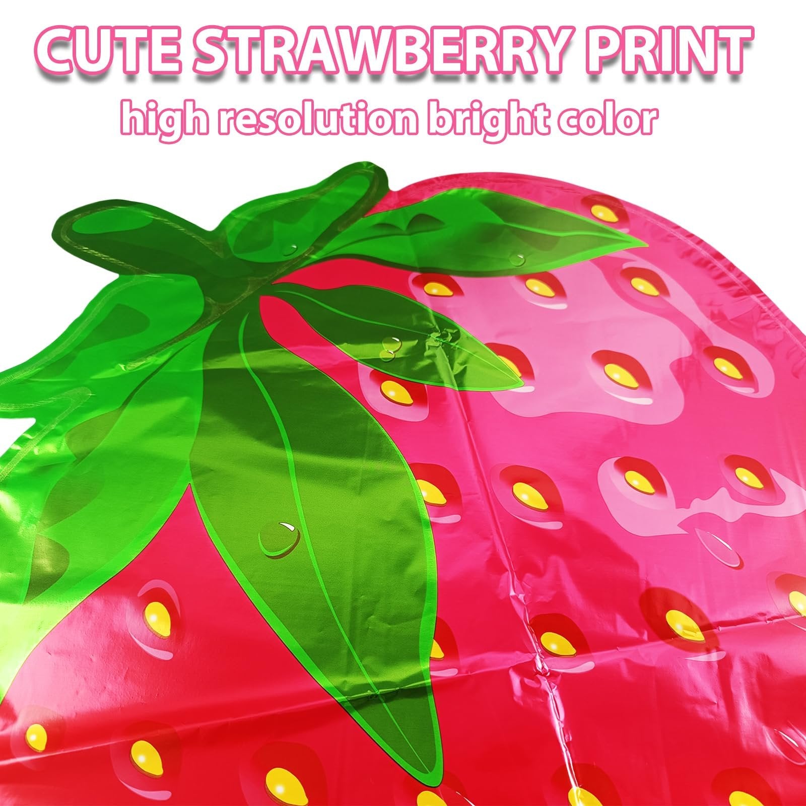 Close-up of a large strawberry-shaped foil balloon with green leaves and pink body, showing seeds.