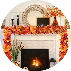 Artificial fall maple leaf garland draped over a fireplace mantel with a lit fire below.