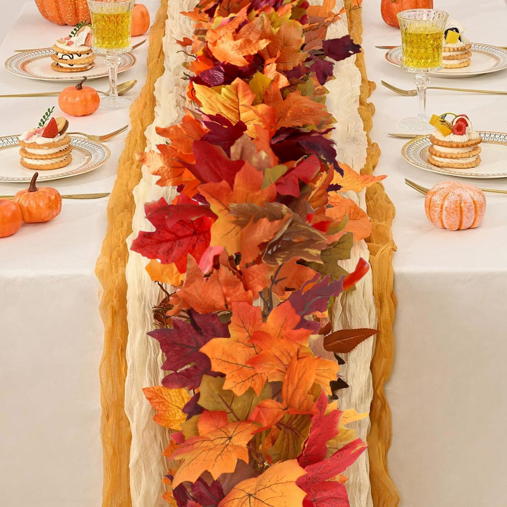 Autumn maple leaf garland draped across a table setting with small cakes and pumpkins