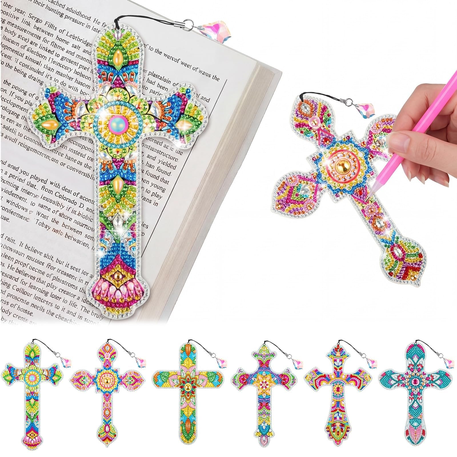 Diamond art cross bookmarks with rhinestones displayed on an open book and a hand holding a pink tool.
