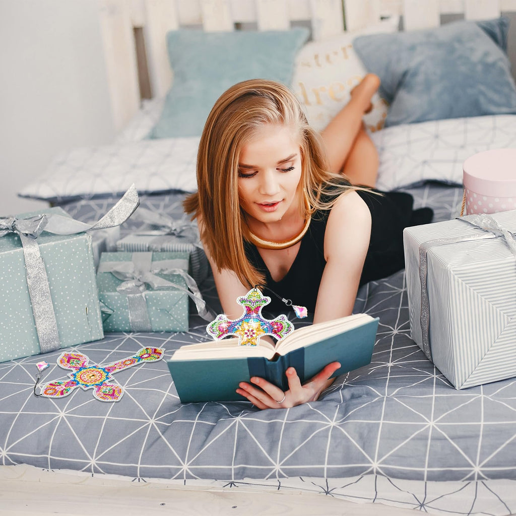 Woman lying on a bed with gifts, reading a book with a diamond art cross bookmark