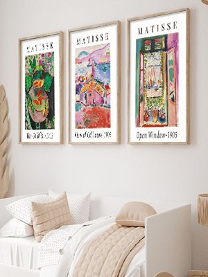 Three framed Matisse art prints hanging on a wall above a bed with neutral bedding.