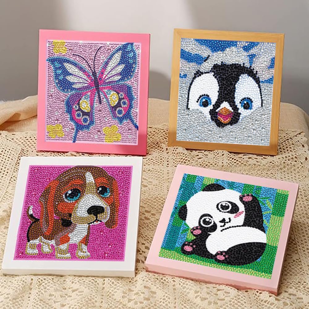 Four framed diamond painting kits featuring a butterfly, penguin, dog, and panda, displayed on a textured surface.