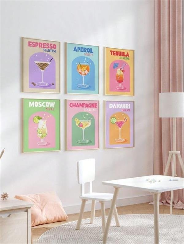 Six framed retro cocktail art prints displayed on a wall above a child's table and chair.