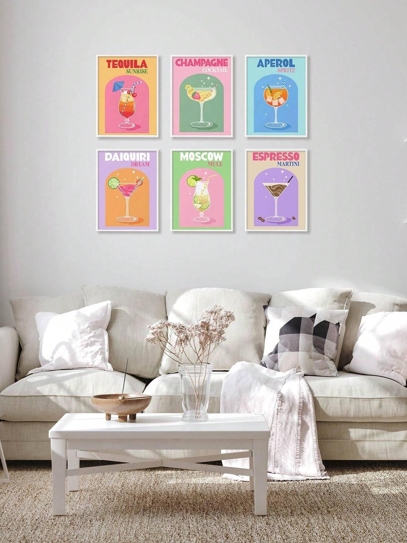 Six framed retro cocktail art prints hanging on a wall above a sofa and coffee table.