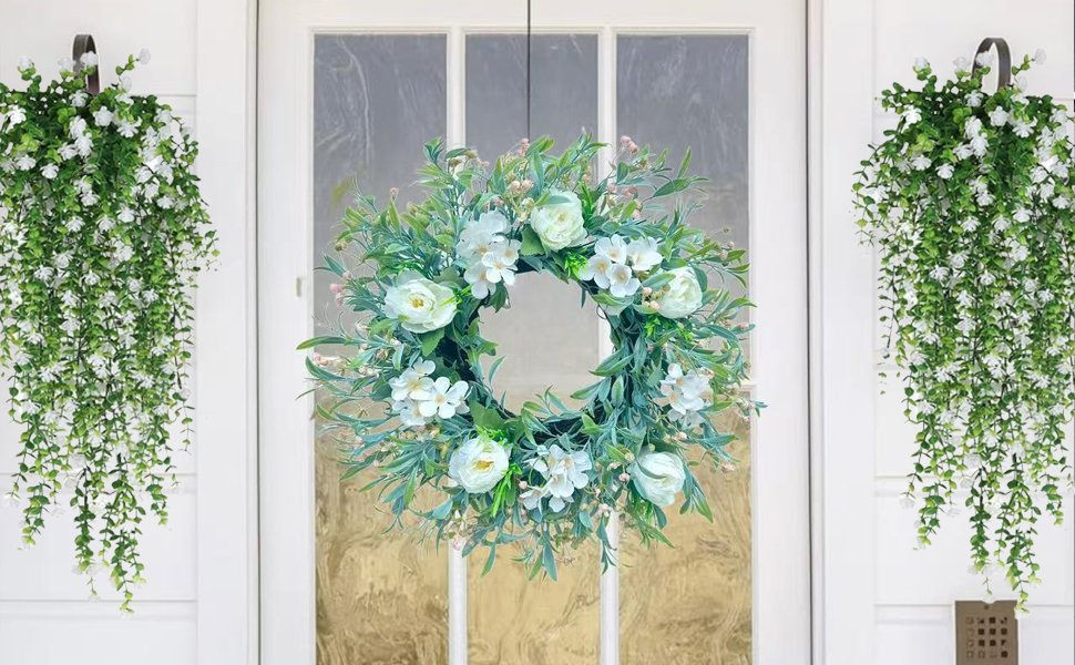 White floral wreath and two hanging greenery cascades on a white door