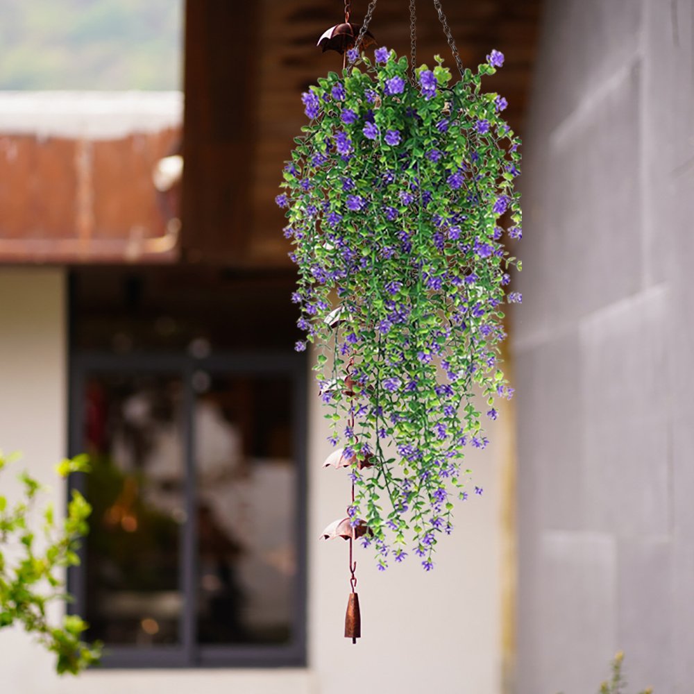 Artificial hanging flowers with faux eucalyptus vine and decorative bells, displayed outdoors.