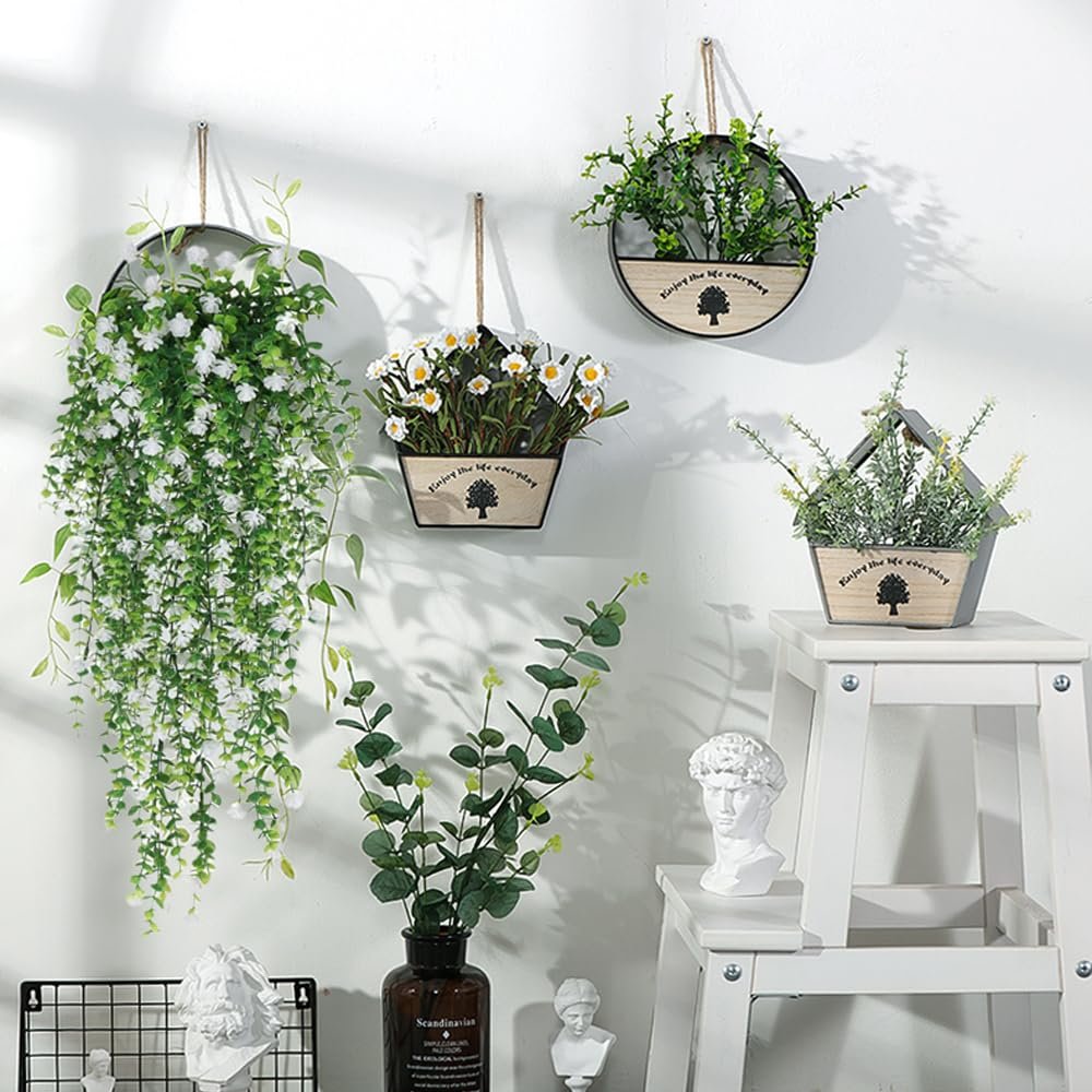 Four hanging planters with artificial plants and greenery displayed on a white wall.