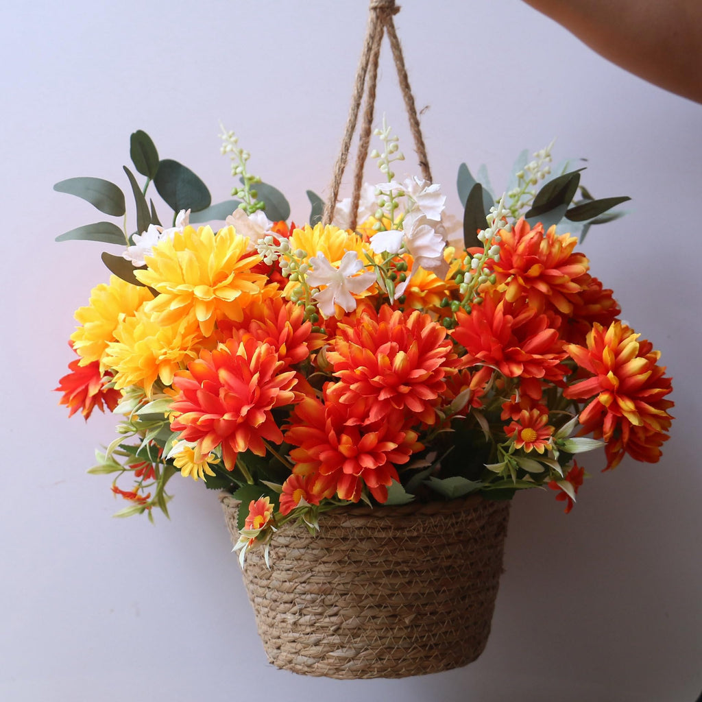 Hanging basket filled with artificial marigold silk flowers in burnt orange and yellow, with green leaves and white accents.