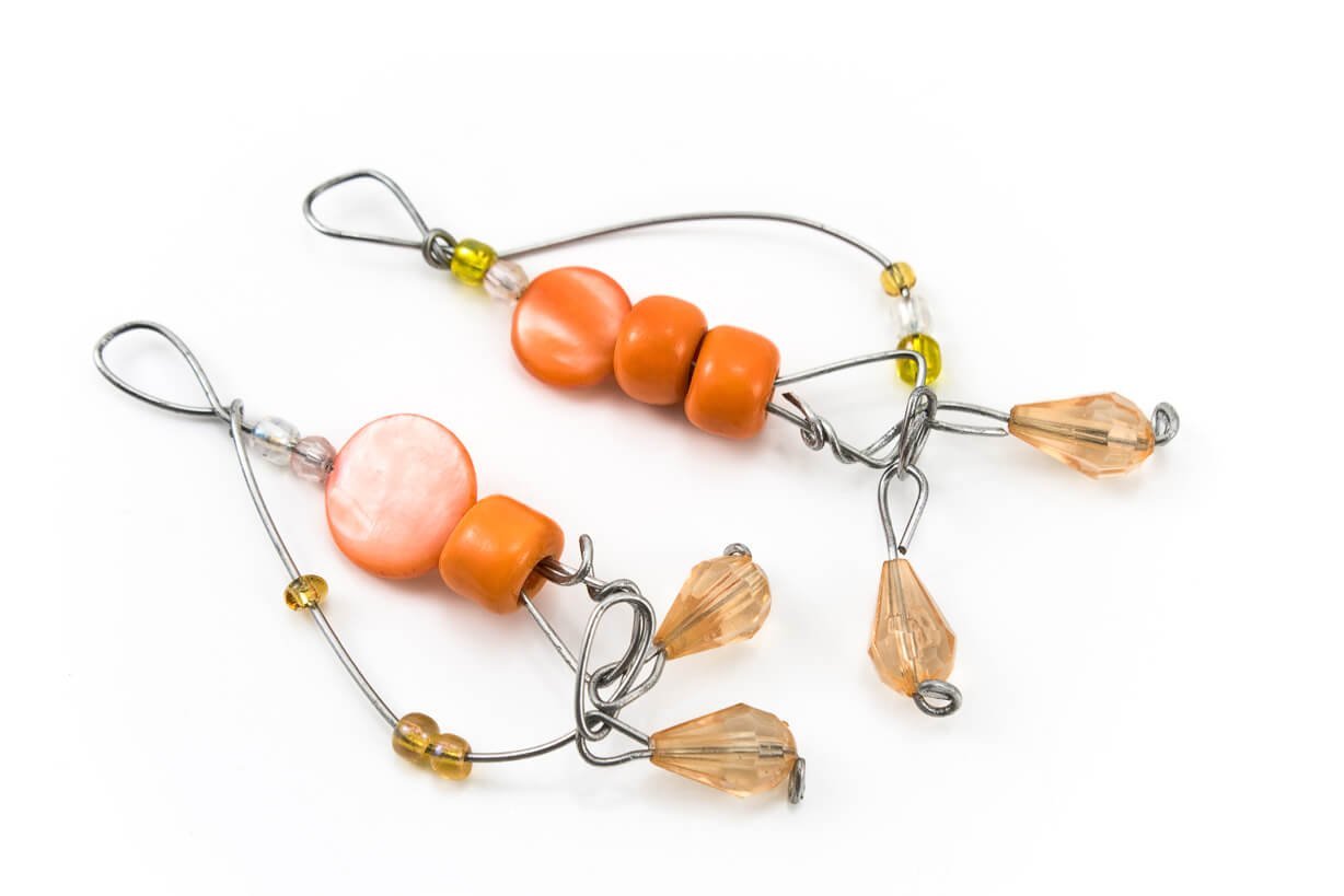 Two jewelry making wire samples with orange and clear beads, on a white background.