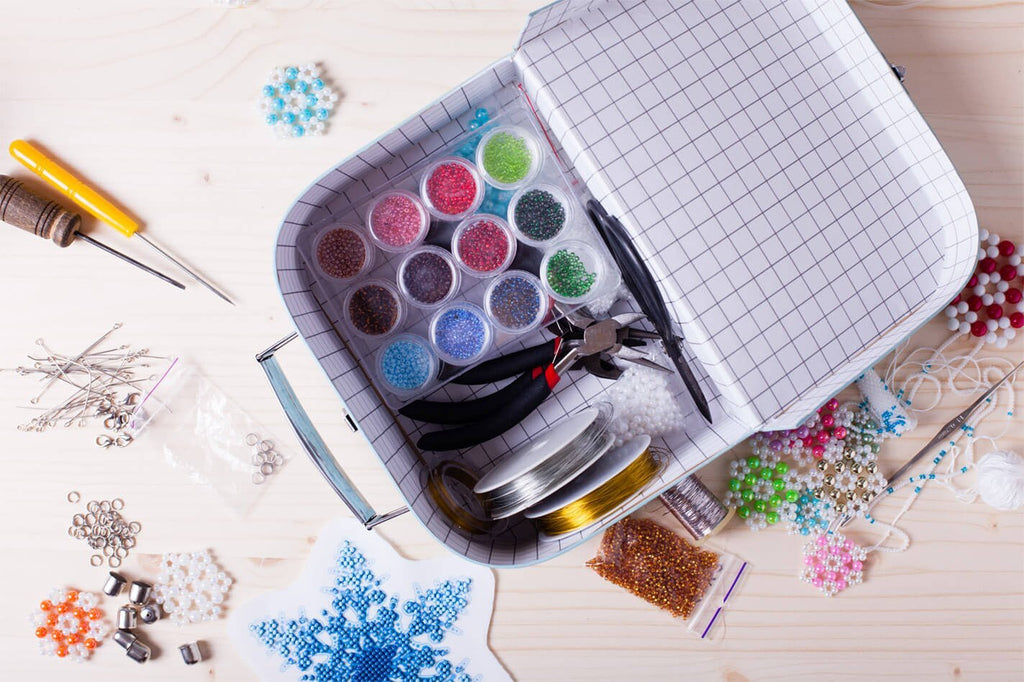 Jewelry making kit with assorted beads, wires, and tools laid out on a wooden surface.