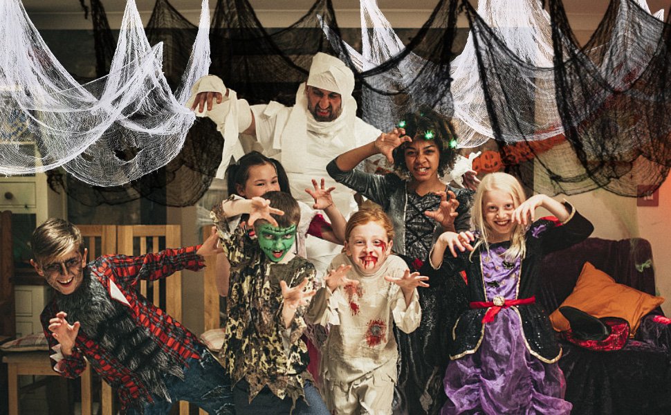 Group of children and an adult in Halloween costumes posing with creepy cloth decorations