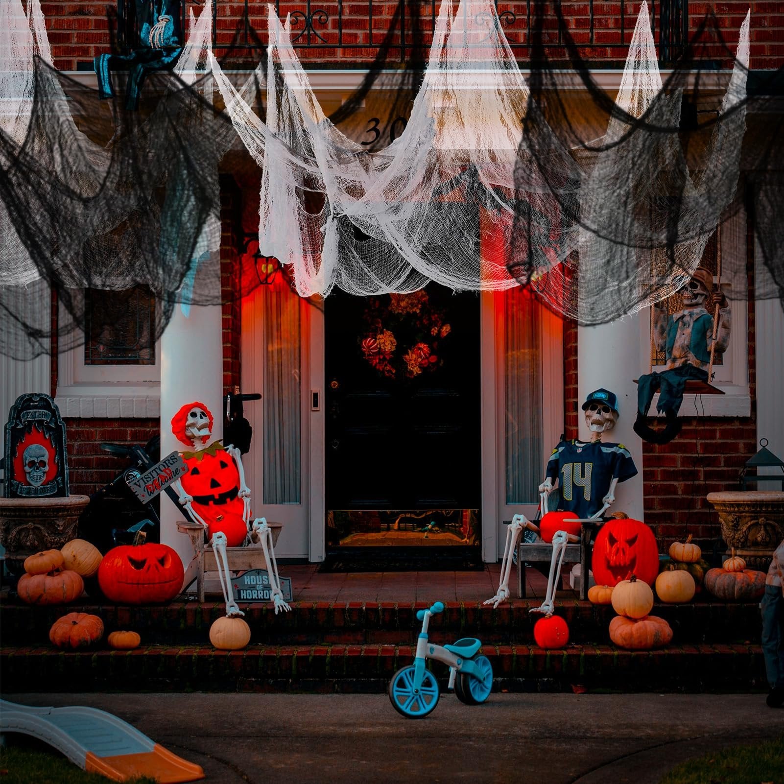 Halloween decorated porch with skeletons, pumpkins, and creepy cloth draped from the roof.