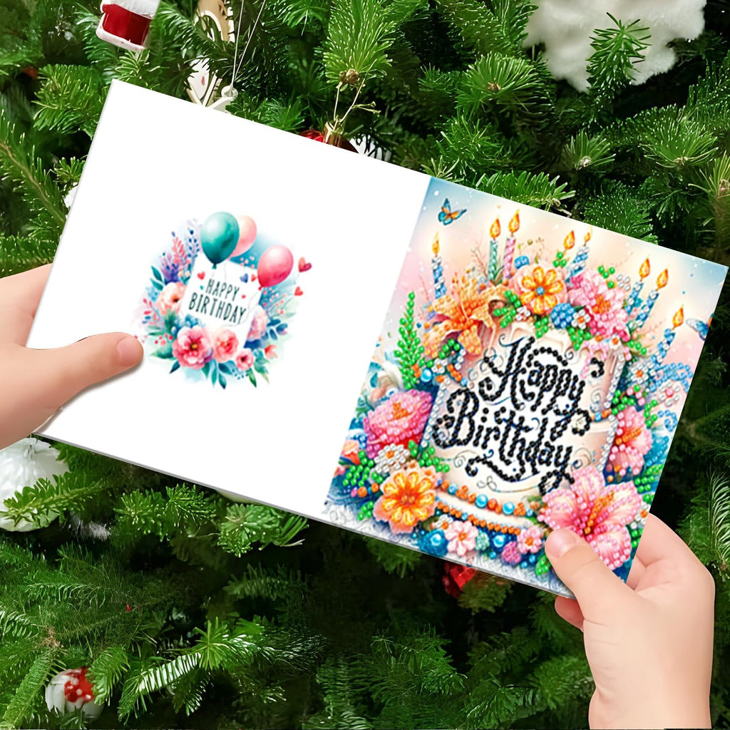 Two diamond painting greeting cards with floral and balloon designs, held in front of a Christmas tree.