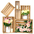 Six wooden crates of varying sizes arranged with decorative flowers and candles, some crates are empty.