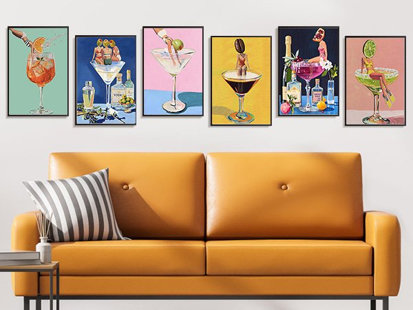 Six framed paint by numbers canvases depicting various cocktails and martini glasses, displayed above a yellow sofa.