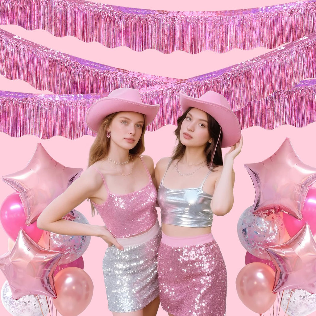 Two young women in pink cowboy hats and sparkly outfits pose with pink balloons and foil fringe garland.