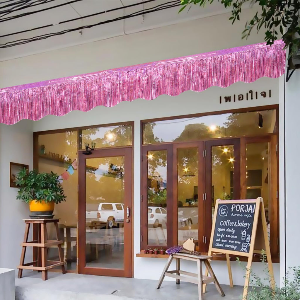 Pink foil fringe garland draped across the front of a building awning.