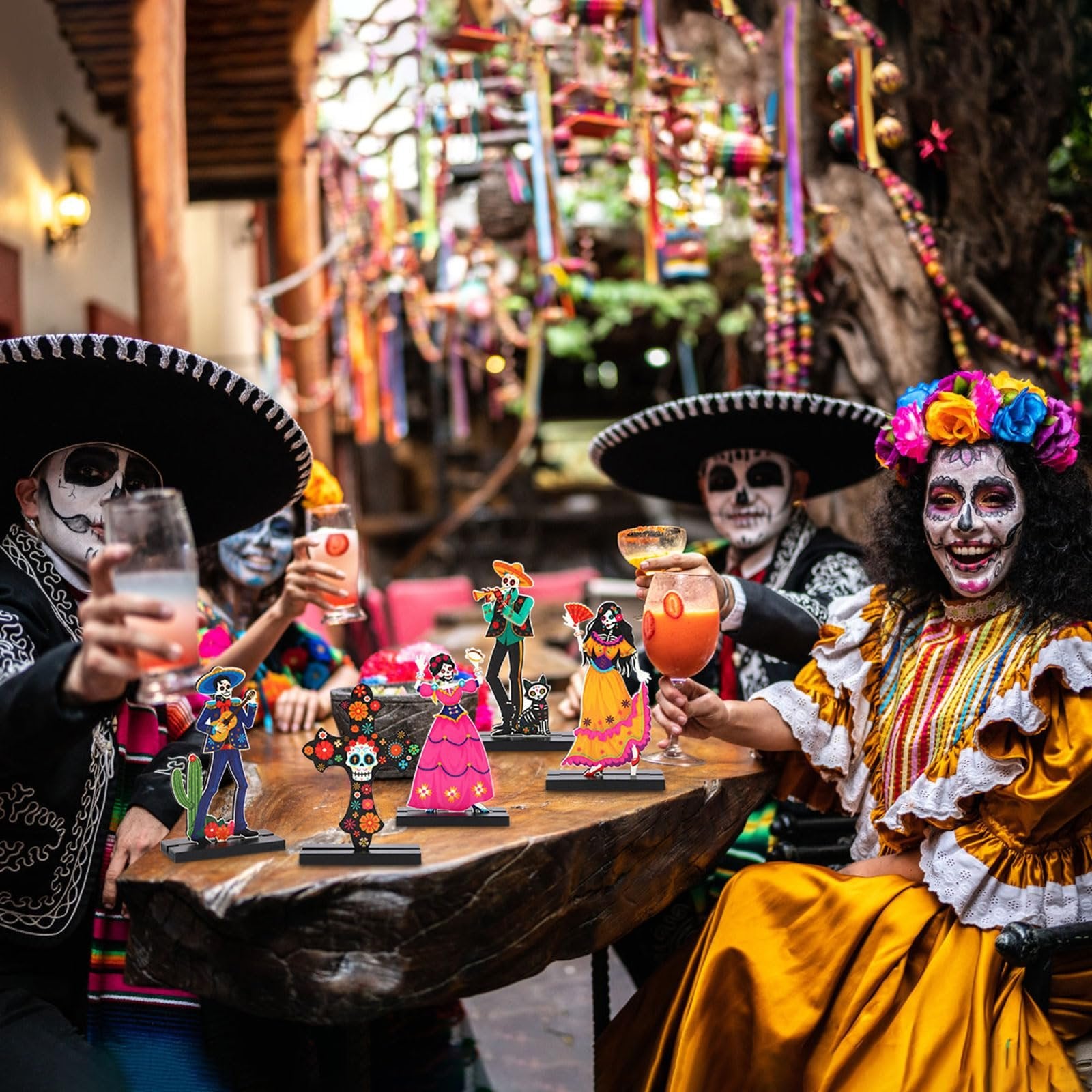 People in Day of the Dead makeup and attire celebrating at a table with sugar skull centerpieces