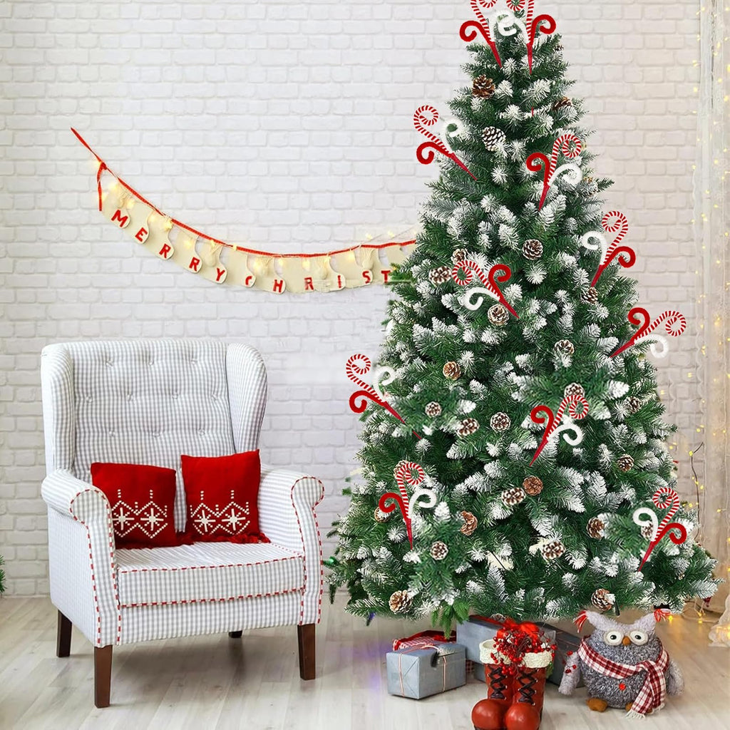 Christmas tree decorated with candy cane picks, pine cones, and artificial snow, next to a chair with red pillows.
