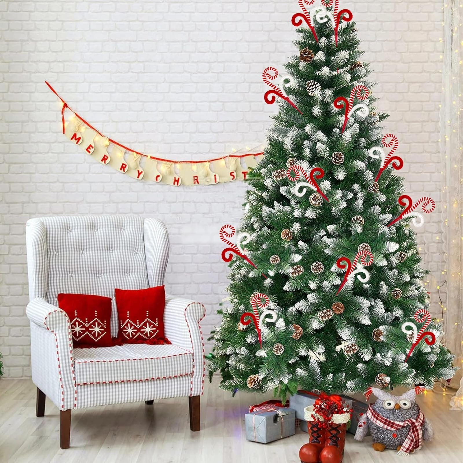 Christmas tree decorated with candy cane picks, pine cones, and artificial snow, next to a chair with red pillows.